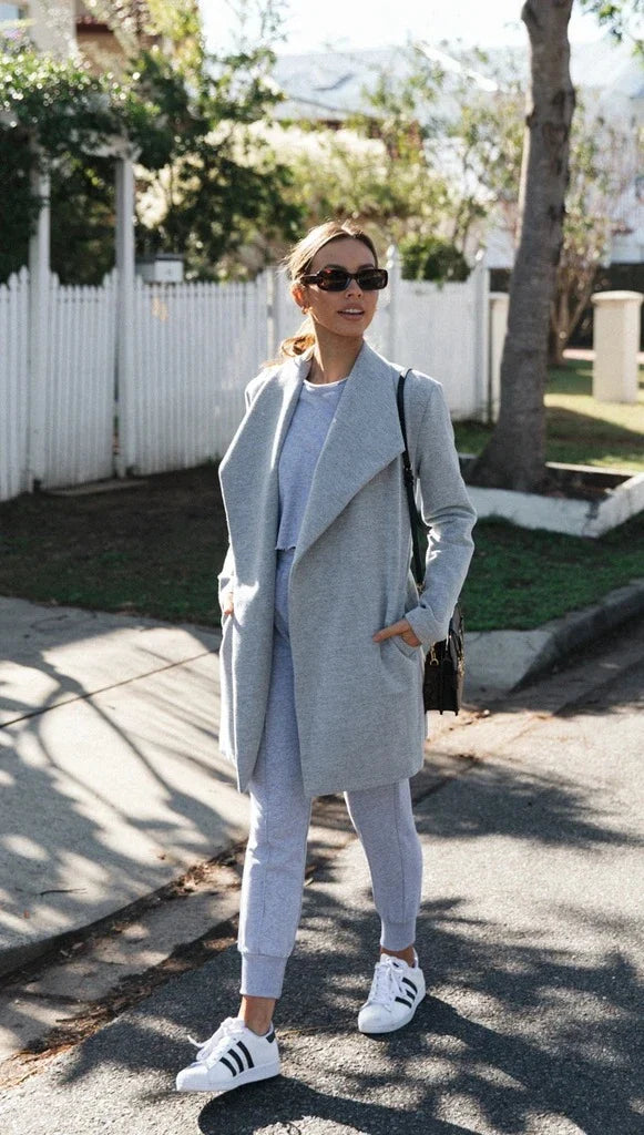 A versatile polyester trench coat in grey, featuring a classic silhouette and convenient design for easy layering over any outfit.