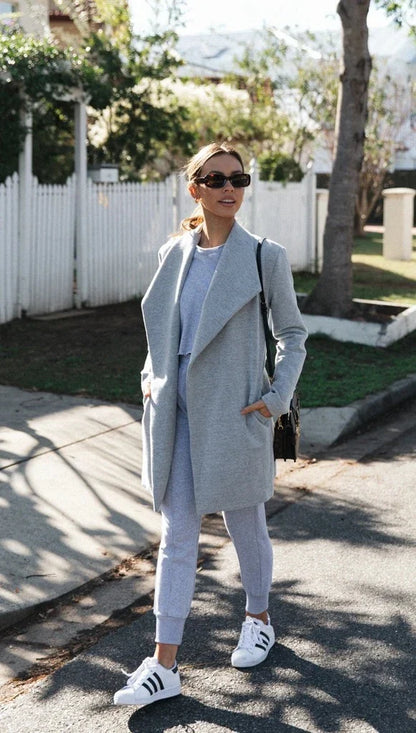 A versatile polyester trench coat in grey, featuring a classic silhouette and convenient design for easy layering over any outfit.