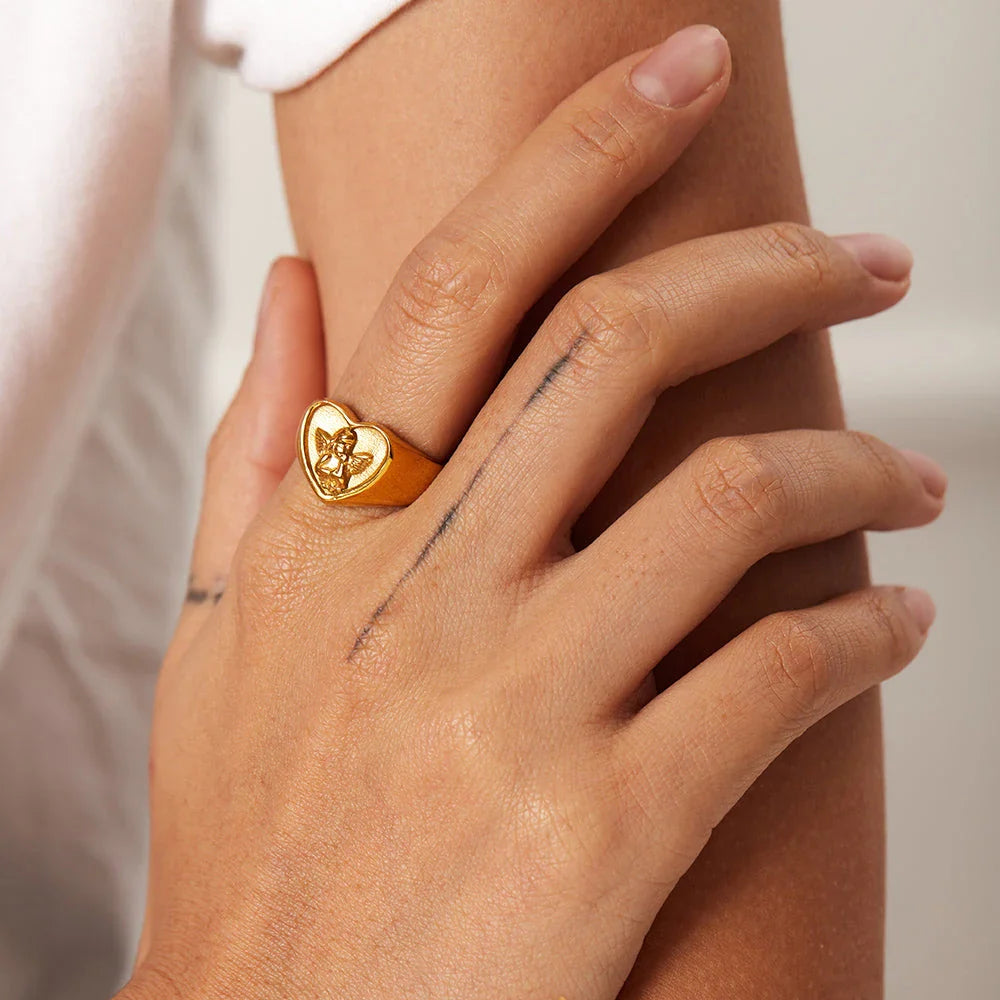 Sophisticated gold-plated stainless steel ring with a geometric heart and angel design, perfect for adding a touch of elegance to any outfit.