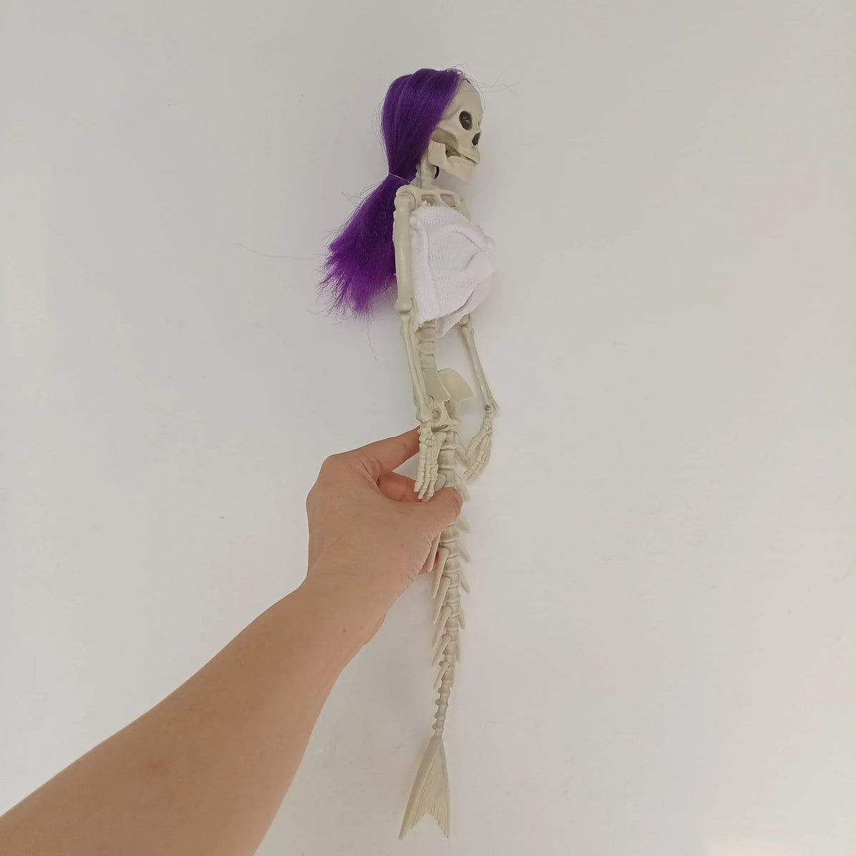 Mermaid bone pendant in various colors, including brown, dark purple, burgundy, and lake blue, hanging outdoors for Halloween decoration