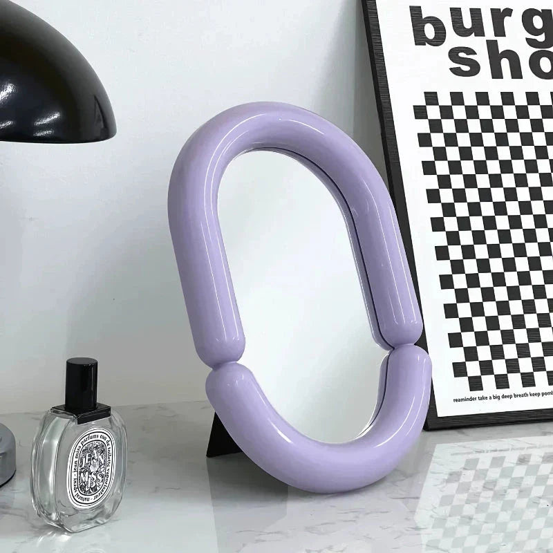 Elegant oval-shaped tabletop mirror with a sleek black plastic frame, perfect for adding a touch of sophistication to any room.