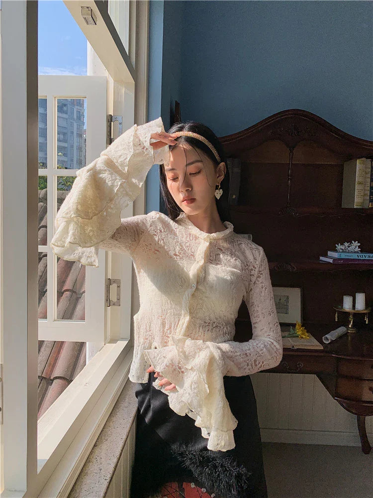 Elegant lace patchwork blouse with ruffled long sleeves and a button-down front in a classic off-white and black color palette.