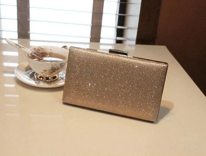 A shiny, metallic dinner clutch bag with a detachable chain strap for versatile carrying options
