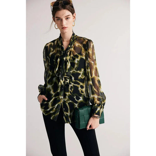 A silk blend blouse with a camouflage print and a bow collar, designed for versatile wear.
