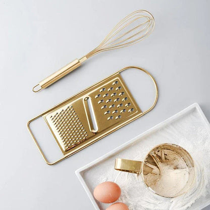 A gold baking tool set including a whisk, scraper, and flour cup made of high-quality stainless steel for versatile and elegant baking needs.