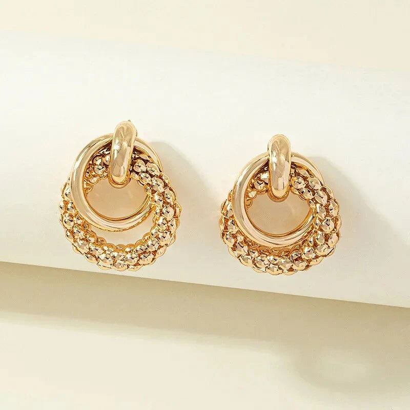 Elegant gold-toned twist dangle earrings with an intricate geometric design, perfect for adding a touch of sophistication to any outfit.