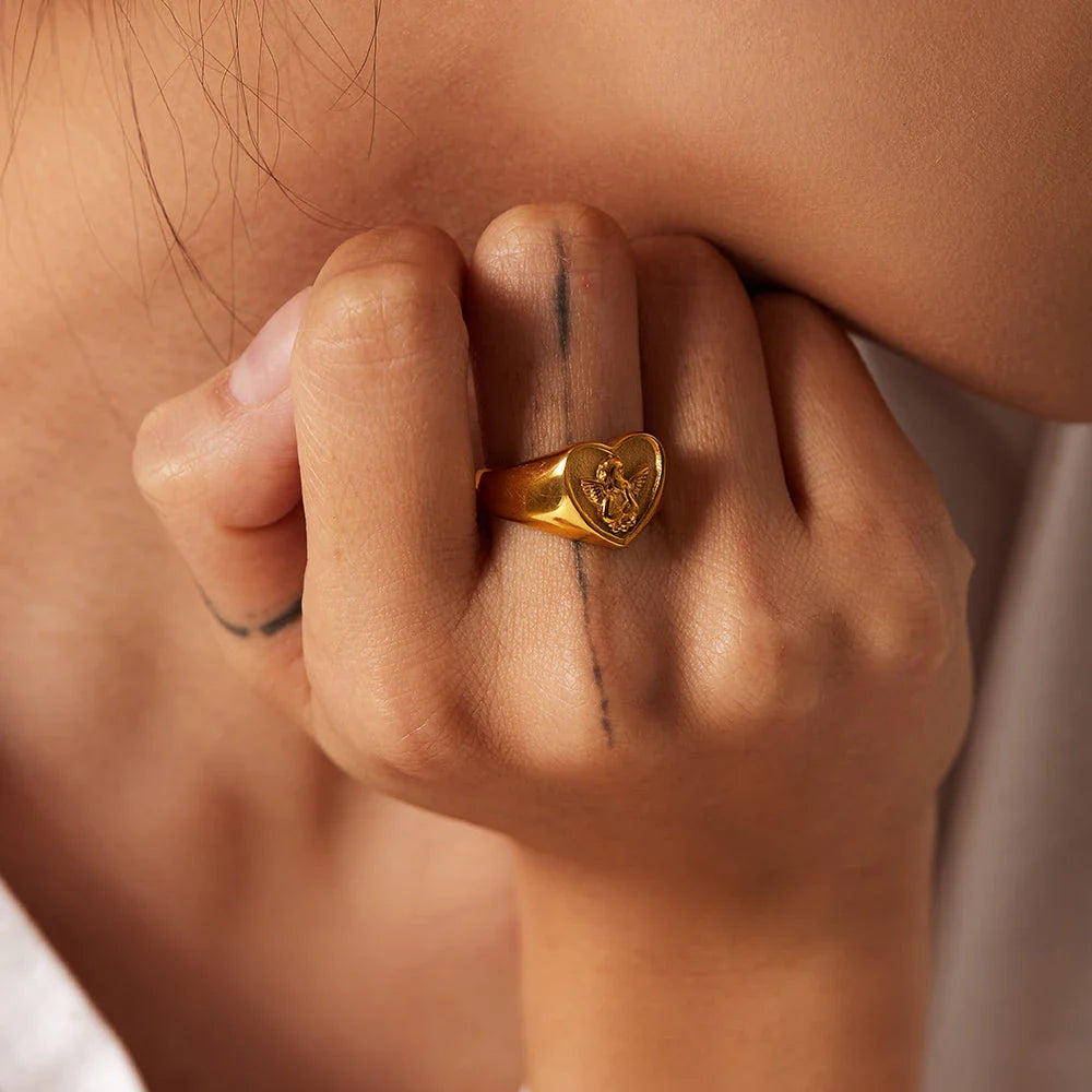 Sophisticated gold-plated stainless steel ring with a geometric heart and angel design, perfect for adding a touch of elegance to any outfit.