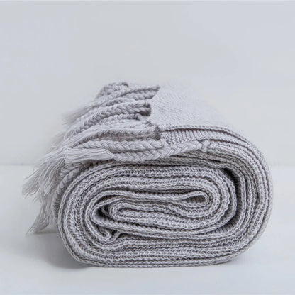 Luxurious Nordic wool knitted throw blanket with tassels in a solid gray color, a cozy and elegant home decor accessory