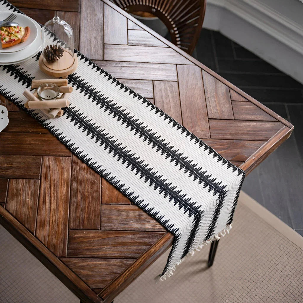Elegant black and white cotton table runner with striped pattern and tassels, perfect for sophisticated dining experiences