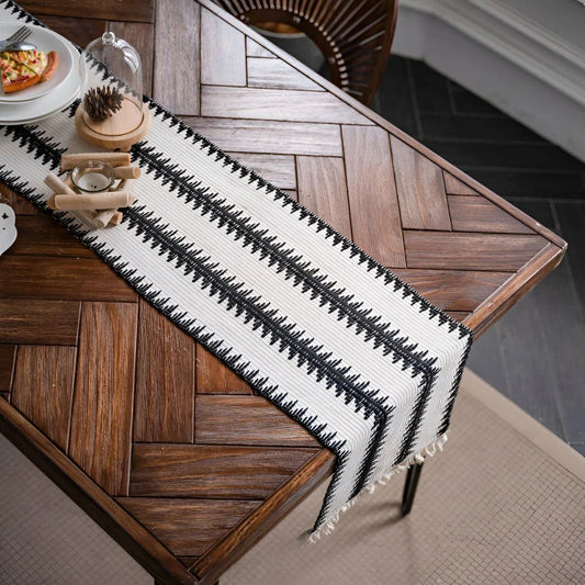 Elegant black and white cotton table runner with striped pattern and tassels, perfect for sophisticated dining experiences