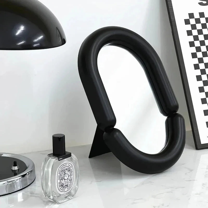 Elegant oval-shaped tabletop mirror with a sleek black plastic frame, perfect for adding a touch of sophistication to any room.