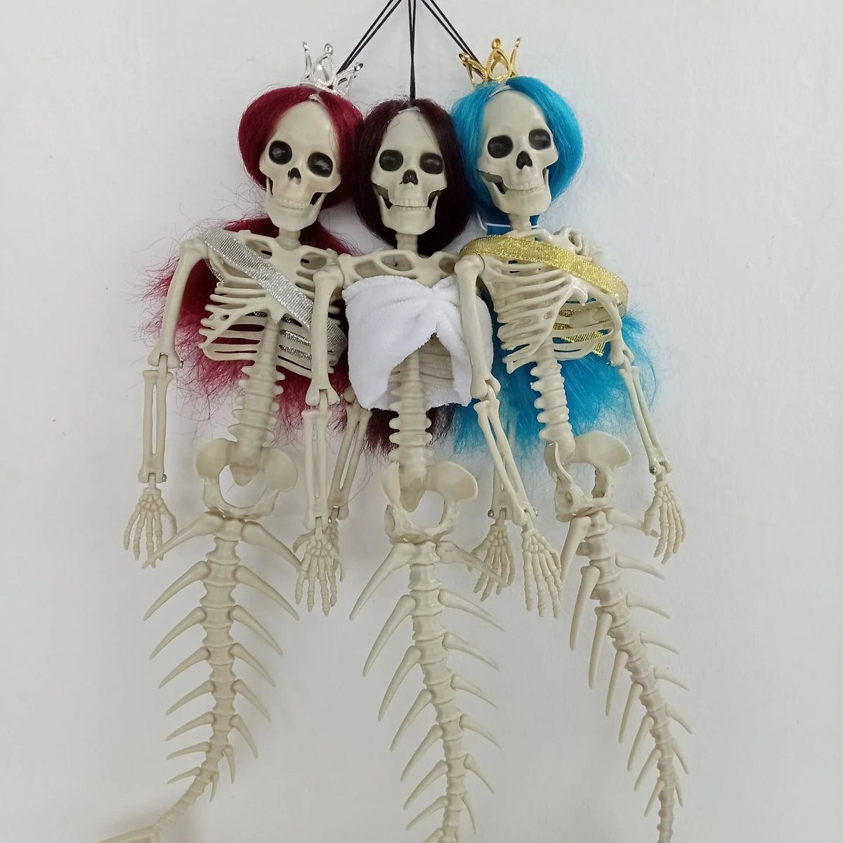 Mermaid bone pendant in various colors, including brown, dark purple, burgundy, and lake blue, hanging outdoors for Halloween decoration
