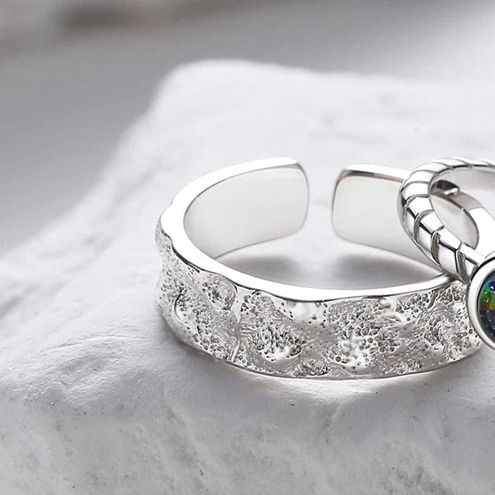A sterling silver couple's ring set featuring a captivating glass design and an adjustable fit