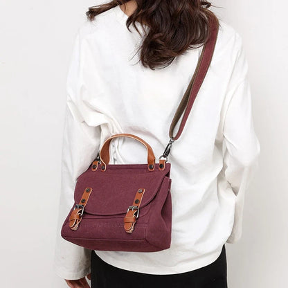 A stylish women's canvas crossbody handbag in an orange color, featuring a small square shape and a horizontal design.