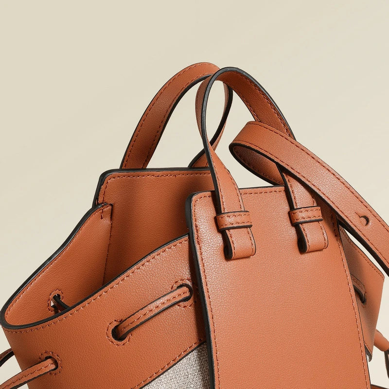 A stylish drawstring bucket bag made from premium cowhide leather and canvas, featuring a spacious main compartment, adjustable shoulder strap, and a softly structured design.