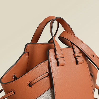 A stylish drawstring bucket bag made from premium cowhide leather and canvas, featuring a spacious main compartment, adjustable shoulder strap, and a softly structured design.