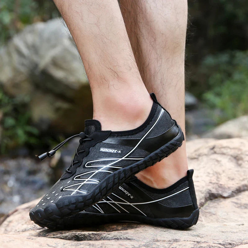 Couple wearing blue, black, and khaki five-finger water shoes, wading in a stream and exploring a rocky beach