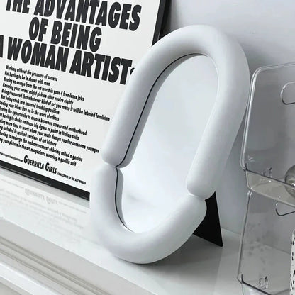 Elegant oval-shaped tabletop mirror with a sleek black plastic frame, perfect for adding a touch of sophistication to any room.