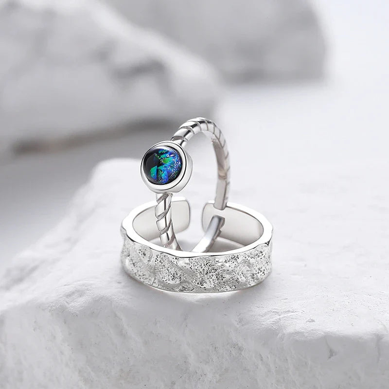 A sterling silver couple's ring set featuring a captivating glass design and an adjustable fit
