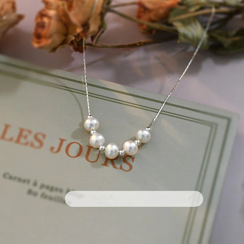 A close-up shot of a natural freshwater pearl necklace with a silver chain in a stylish multi-chain design.