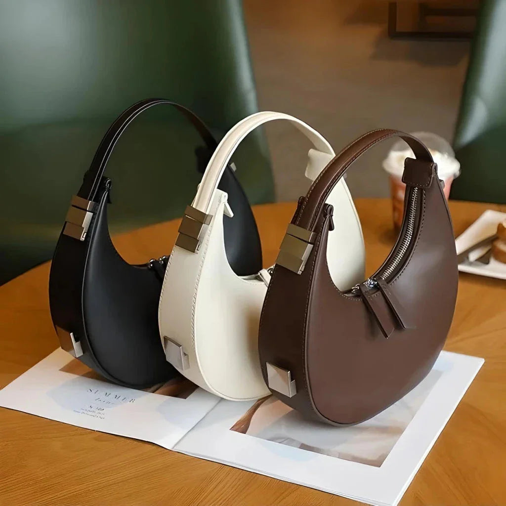 Elegant leather shoulder bag in a half-moon shape, featuring a sleek polyester lining and organized interior pockets for modern women's fashion.