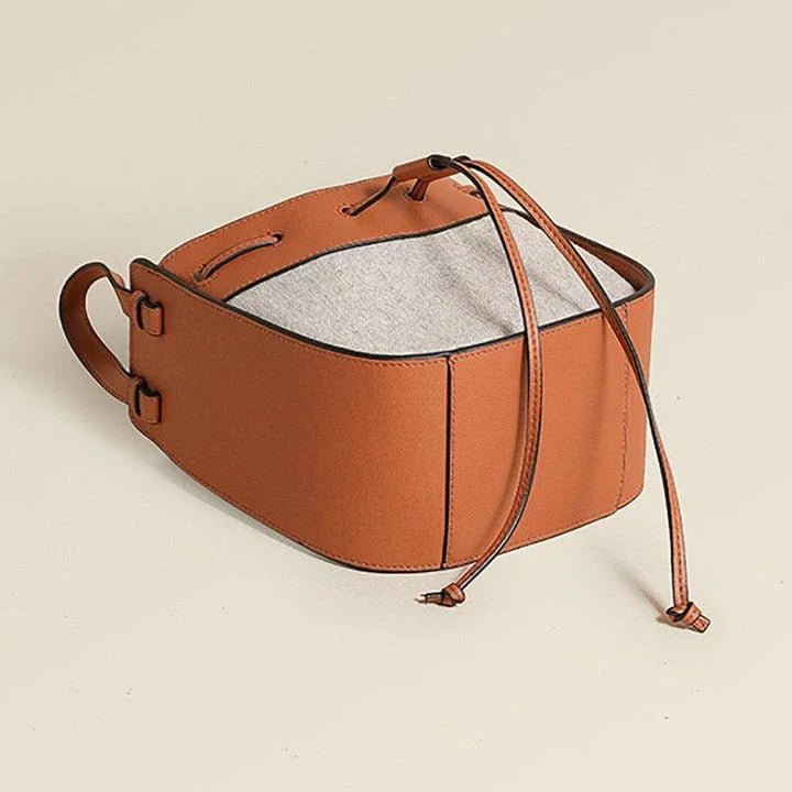 A stylish drawstring bucket bag made from premium cowhide leather and canvas, featuring a spacious main compartment, adjustable shoulder strap, and a softly structured design.
