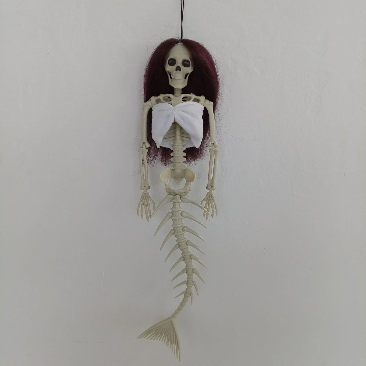 Mermaid bone pendant in various colors, including brown, dark purple, burgundy, and lake blue, hanging outdoors for Halloween decoration