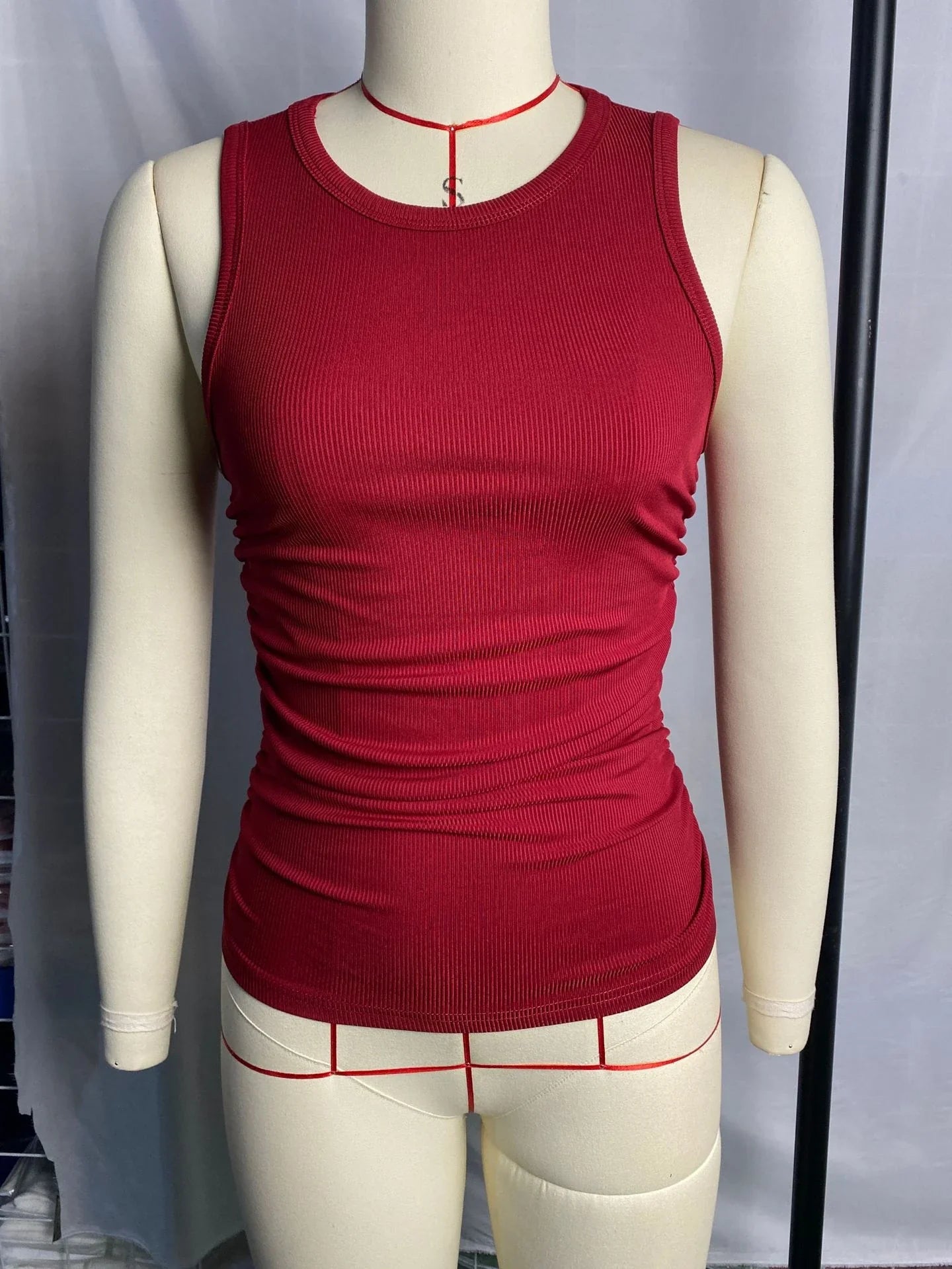 A sleeveless ribbed knit tank top for women in a variety of colors and sizes, featuring a crew neck design and pleated details for a stylish, casual look.