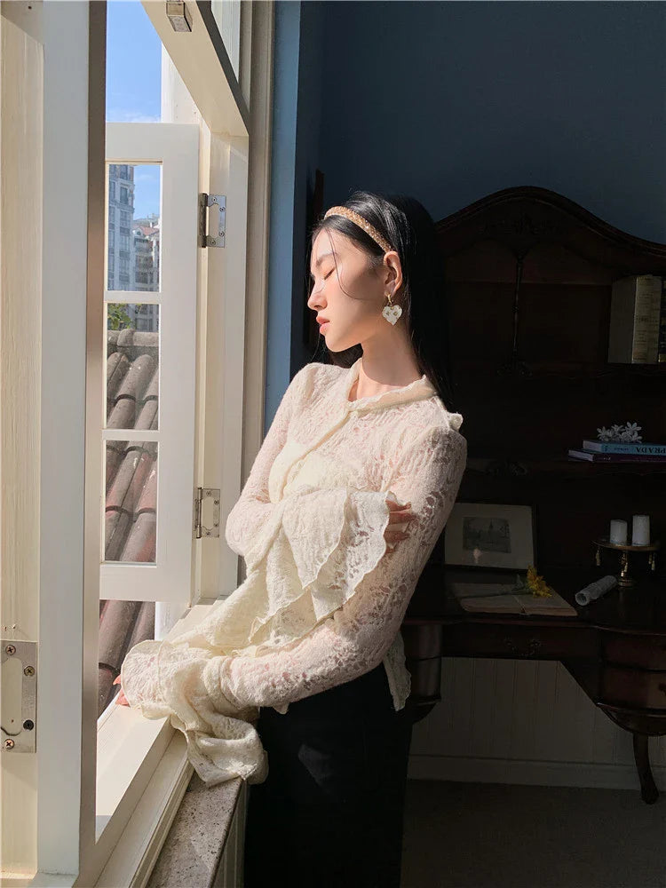 Elegant lace patchwork blouse with ruffled long sleeves and a button-down front in a classic off-white and black color palette.
