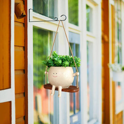A charming face-shaped hanging planter with a swing design, perfect for adding personality and greenery to any indoor or outdoor space.