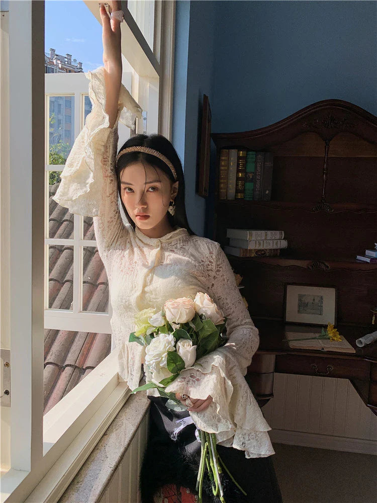 Elegant lace patchwork blouse with ruffled long sleeves and a button-down front in a classic off-white and black color palette.