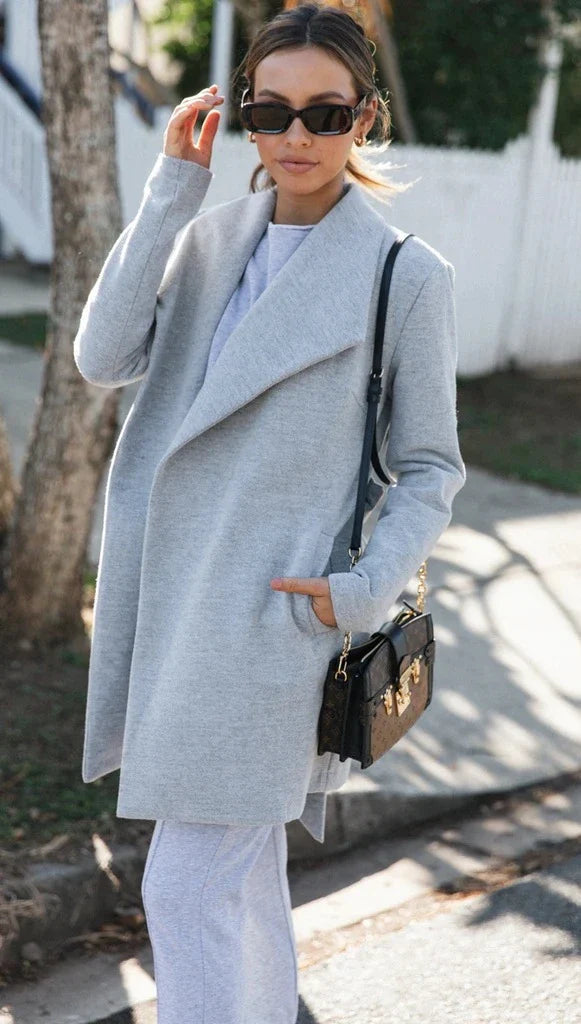 A versatile polyester trench coat in grey, featuring a classic silhouette and convenient design for easy layering over any outfit.