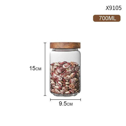 Airtight glass food storage jars with wooden lids in various sizes, perfect for organizing and preserving dry goods, spices, and pantry items in the kitchen.