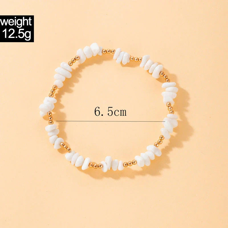 A pair of boho-inspired anklets adorned with natural shells and crushed stones, showcasing a unique geometric design for effortless summer style.