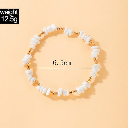 A pair of boho-inspired anklets adorned with natural shells and crushed stones, showcasing a unique geometric design for effortless summer style.