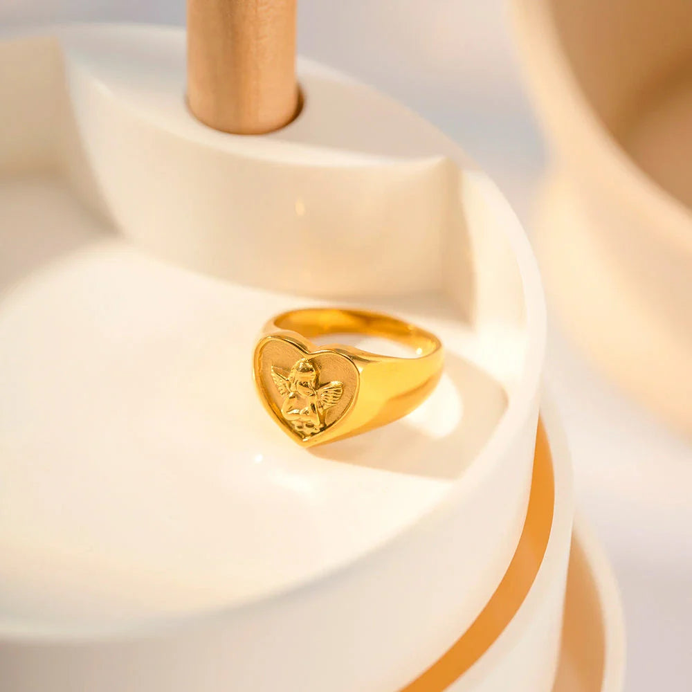Sophisticated gold-plated stainless steel ring with a geometric heart and angel design, perfect for adding a touch of elegance to any outfit.