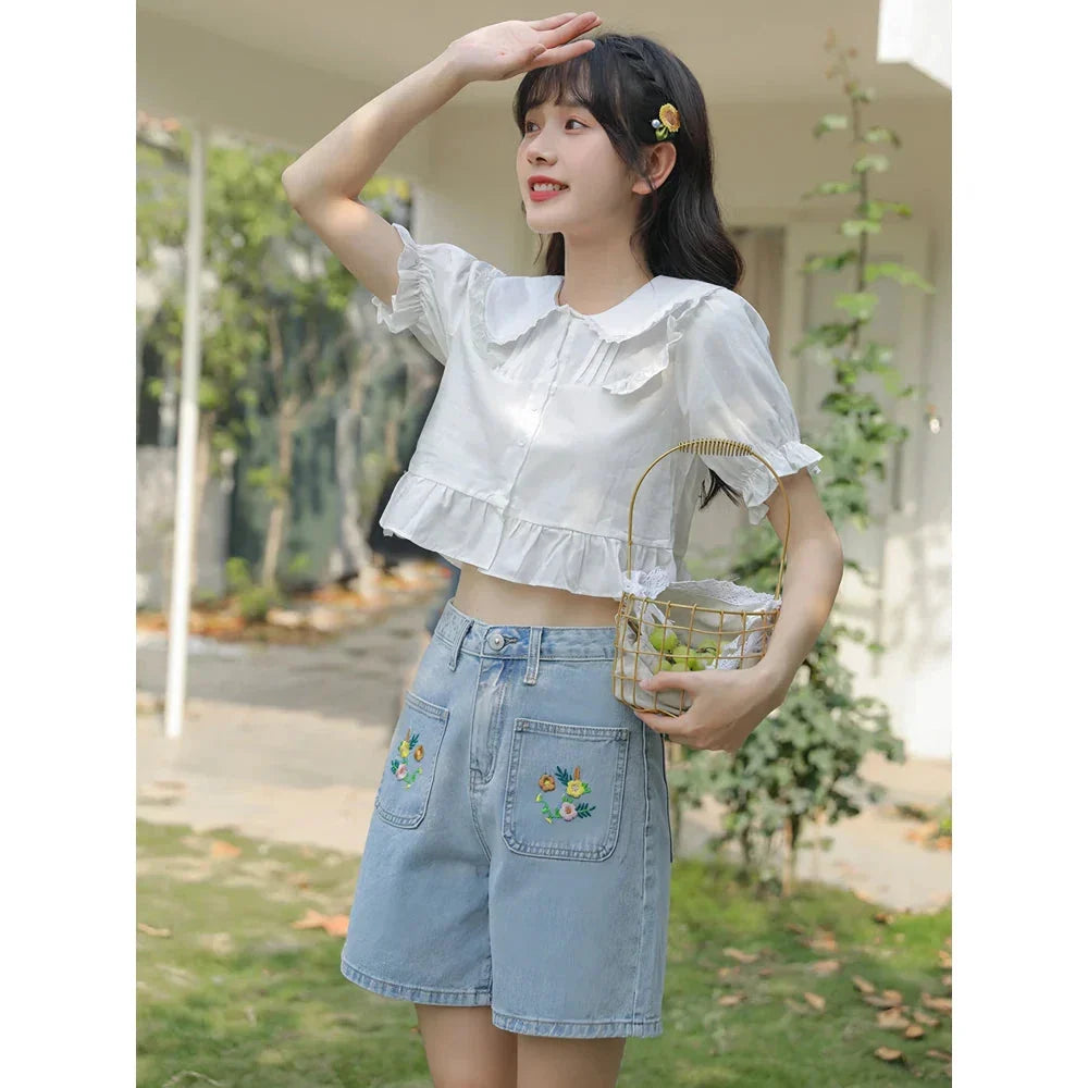 Light blue denim shorts with delicate floral embroidery, providing a stylish and comfortable summer look for women.