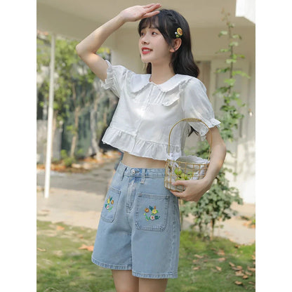 Light blue denim shorts with delicate floral embroidery, providing a stylish and comfortable summer look for women.