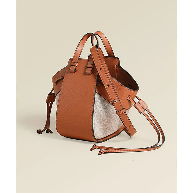 A stylish drawstring bucket bag made from premium cowhide leather and canvas, featuring a spacious main compartment, adjustable shoulder strap, and a softly structured design.