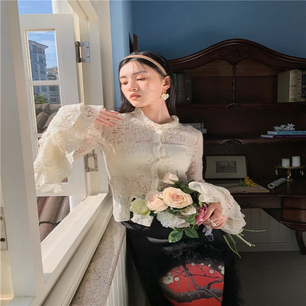 Elegant lace patchwork blouse with ruffled long sleeves and a button-down front in a classic off-white and black color palette.