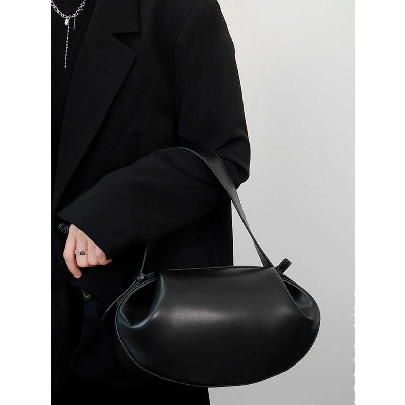 Circular vegan leather handbag in a tan color, with a sturdy build and thoughtful interior design for versatile use.