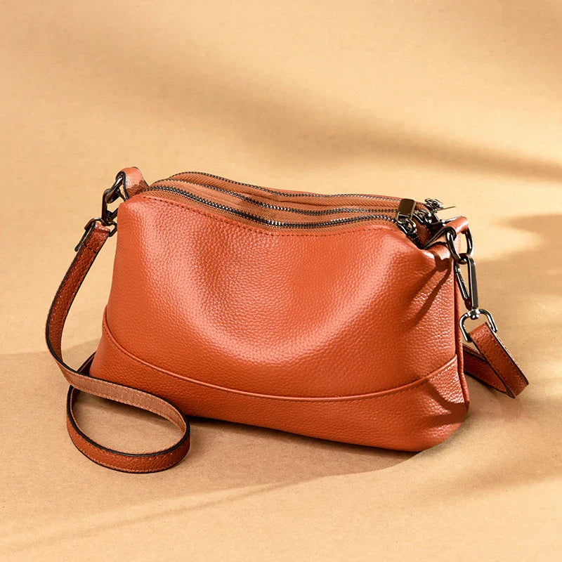 Cowhide shoulder bag in various colors, featuring a sleek and modern design with multiple internal pockets for organization.