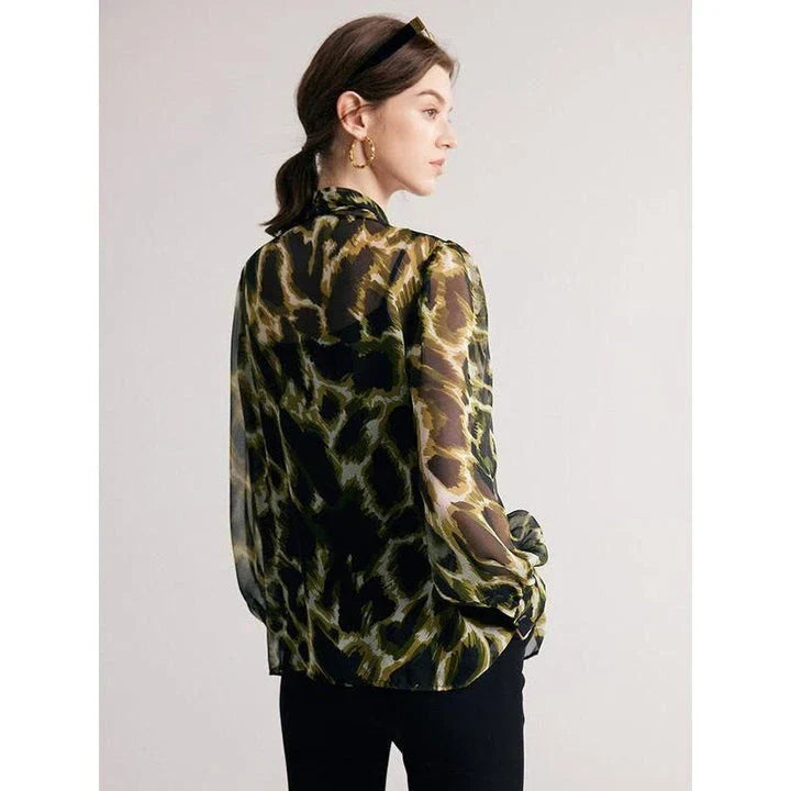 A silk blend blouse with a camouflage print and a bow collar, designed for versatile wear.