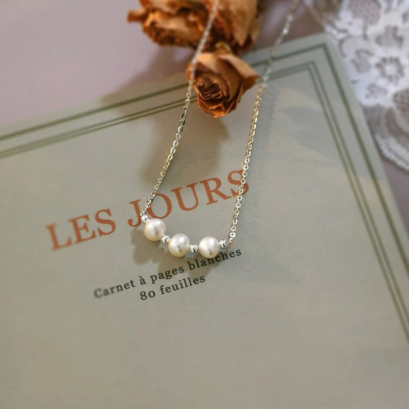 A close-up shot of a natural freshwater pearl necklace with a silver chain in a stylish multi-chain design.