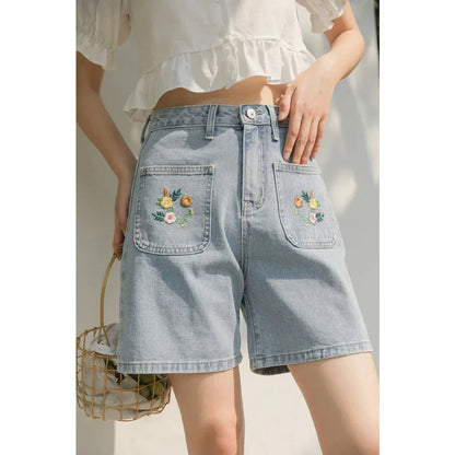 Light blue denim shorts with delicate floral embroidery, providing a stylish and comfortable summer look for women.