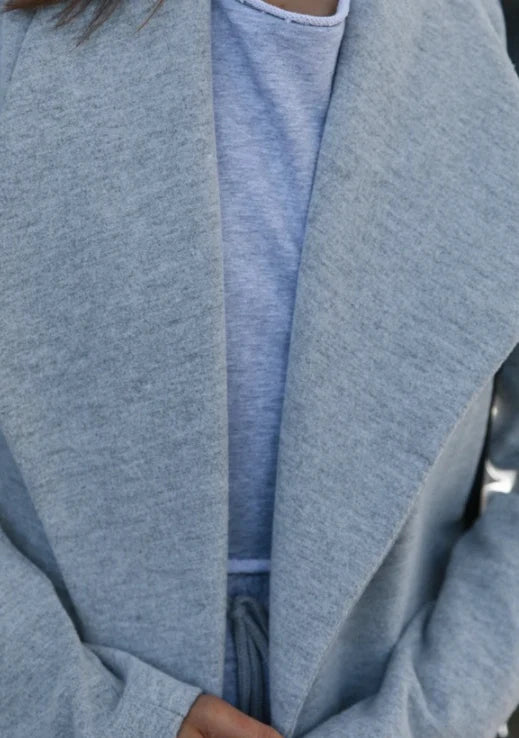 A versatile polyester trench coat in grey, featuring a classic silhouette and convenient design for easy layering over any outfit.