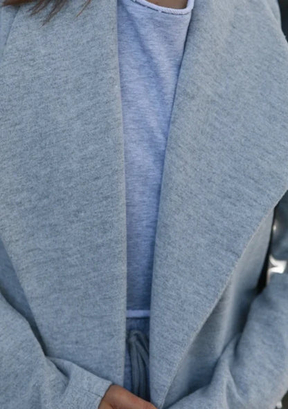 A versatile polyester trench coat in grey, featuring a classic silhouette and convenient design for easy layering over any outfit.