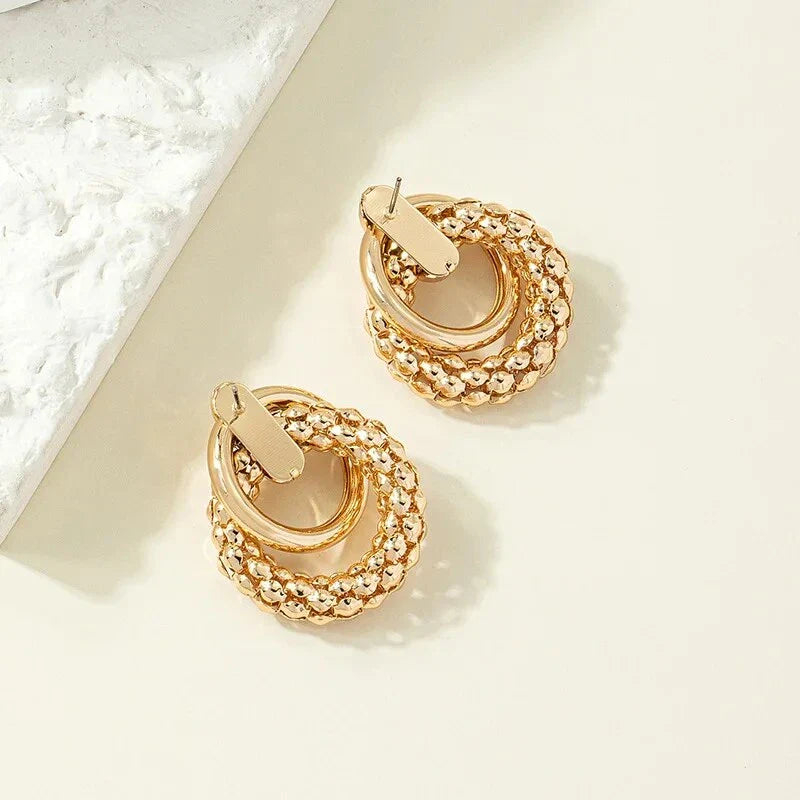 Elegant gold-toned twist dangle earrings with an intricate geometric design, perfect for adding a touch of sophistication to any outfit.