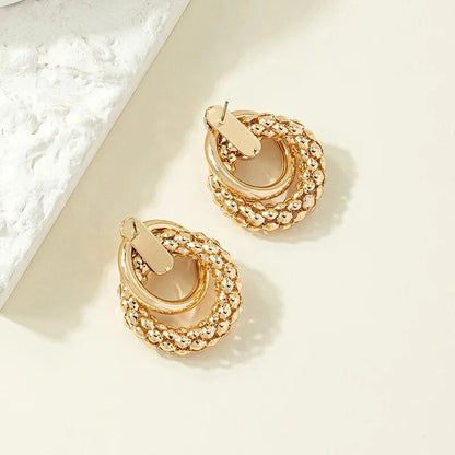 Elegant gold-toned twist dangle earrings with an intricate geometric design, perfect for adding a touch of sophistication to any outfit.