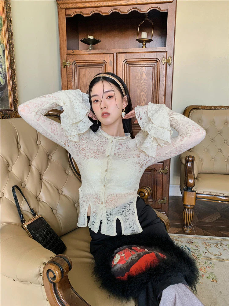 Elegant lace patchwork blouse with ruffled long sleeves and a button-down front in a classic off-white and black color palette.